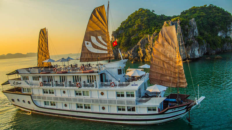 Båten Bhaya Classic i Ha Long bukten bland gröna klippor. 